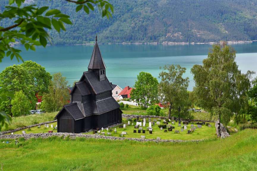 Eine Kirche mit einem Friedhof davor und einem See im Hintergrund