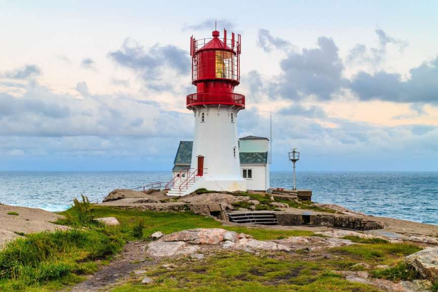 Ein rot-weißer Leuchtturm steht auf einem Felsen in der Nähe des Ozeans