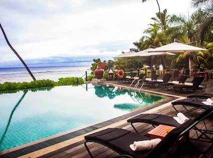 Ein Infinity-Pool mit Liegestühlen und Sonnenschirmen neben dem Ozean .