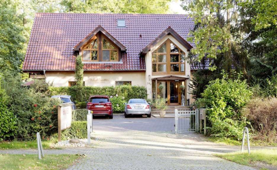 Ein Hotel mit rotem Ziegeldach und zwei Autos davor.