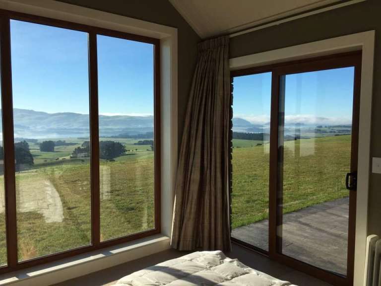 Ein Schlafzimmer mit einer Schiebetür und einem Blick auf eine Wiese