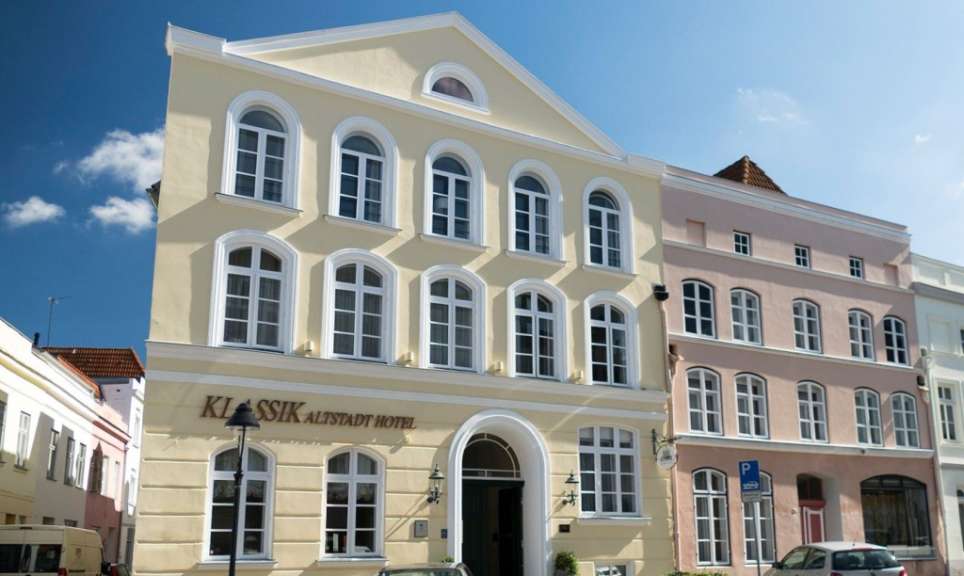 Ein gelbes Gebäude mit weißen Fenstern und einer blauen Himmelkulisse.