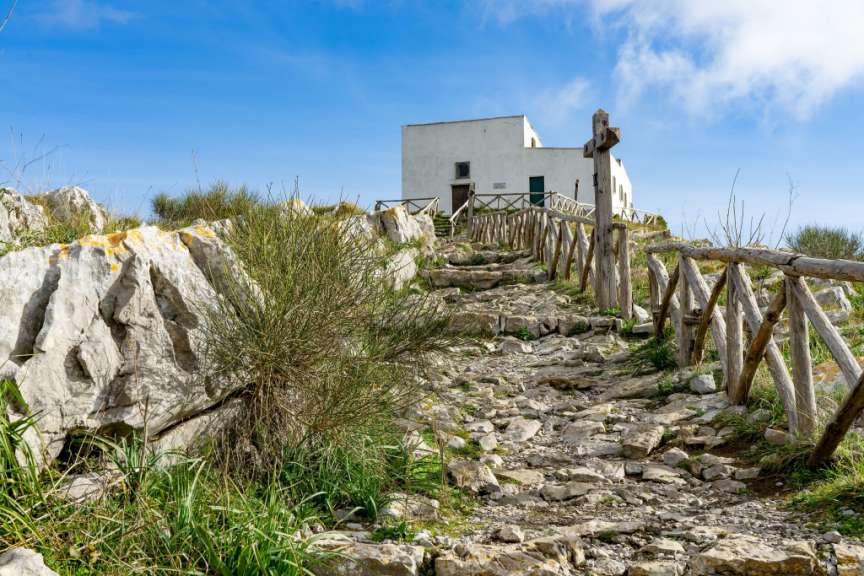 Ein Steinweg mit einem Holzzaun und einem weißen Gebäude im Hintergrund