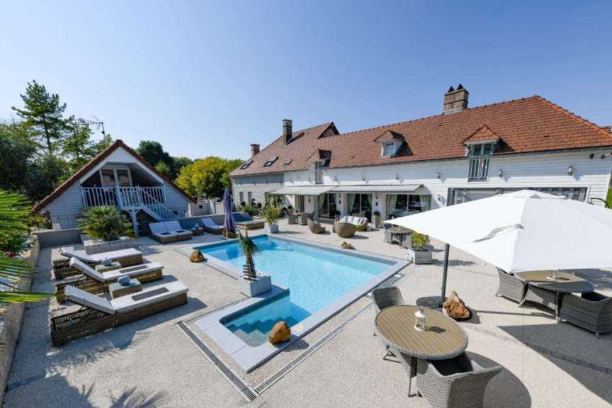 Ein großes Haus mit einem großen Pool und einem Tisch und Stühlen