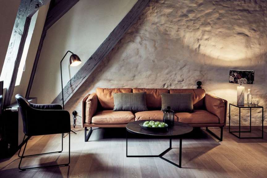Ein Wohnzimmer mit einem braunen Ledersofa und einem schwarzen Stuhl