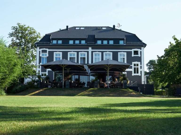 Ein großes schwarz-weißes Gebäude mit vielen Sonnenschirmen davor