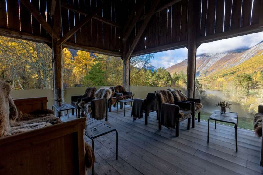 Eine hölzerne Veranda mit Stühlen und Tischen mit Blick auf die Berge