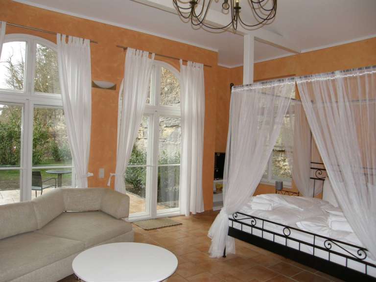 Ein Schlafzimmer mit einem Himmelbett und vielen Fenstern