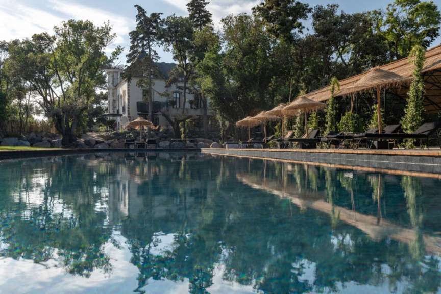 Ein großer Swimmingpool mit Liegestühlen und Sonnenschirmen umgeben