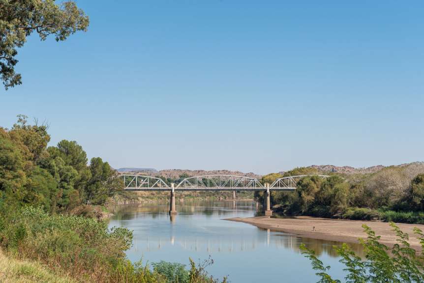 Eine Brücke über einen Fluss mit Bäumen im Hintergrund