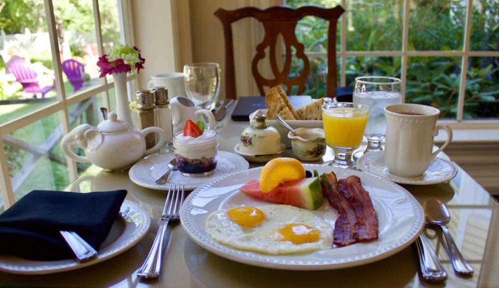 Ein Frühstückstisch mit einem Teller mit Eiern und Speck