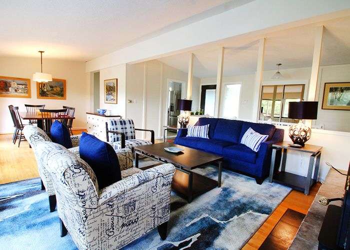 Ein Wohnzimmer mit einer blauen Couch und zwei Stühlen