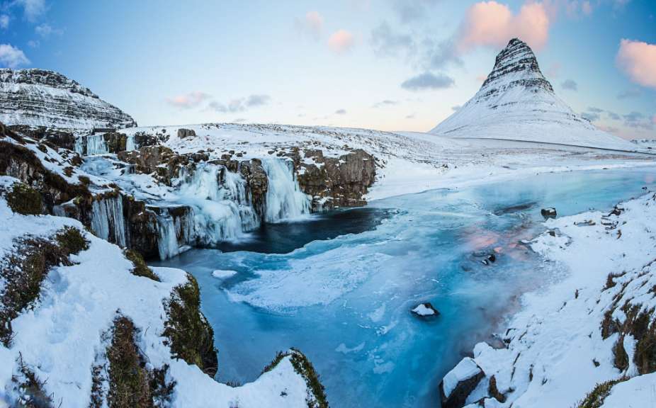 Ein schneebedeckter Wasserfall mit einem schneebedeckten Berg im Hintergrund