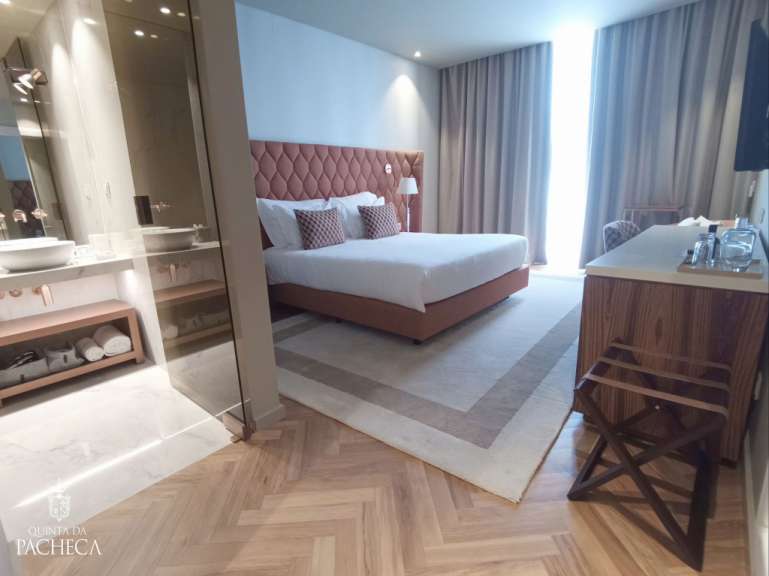 Ein luxuriöses Hotelzimmer mit einem großen Bett, einem Badezimmerbereich und einem Teppichboden.