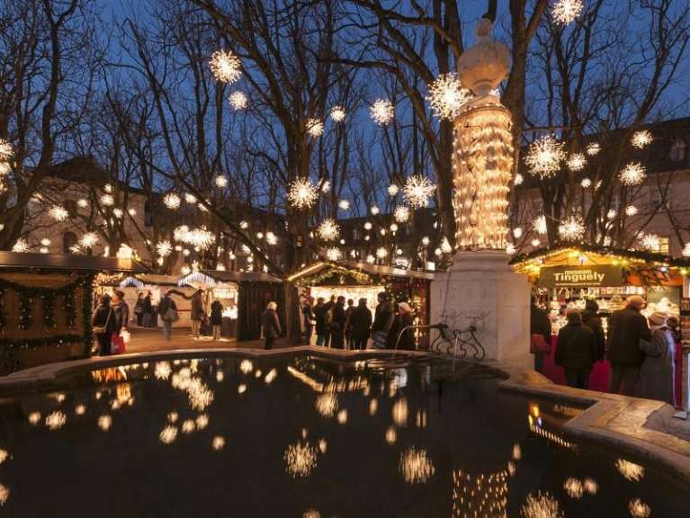 Eine Gruppe von Menschen steht vor einem weihnachtsmarkt und steht neben einem Brunnen