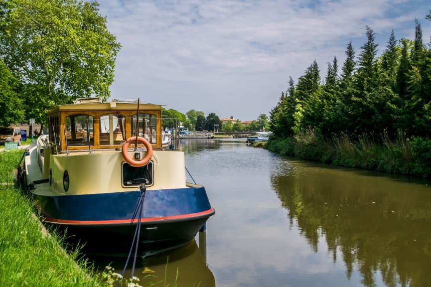Ein blau-weißes Boot mit einem weißen Ring am Bug steht an einem Fluss
