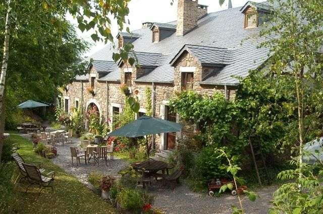 Ein Steinhaus mit Tisch und Stühlen und Regenschirmen vorne .