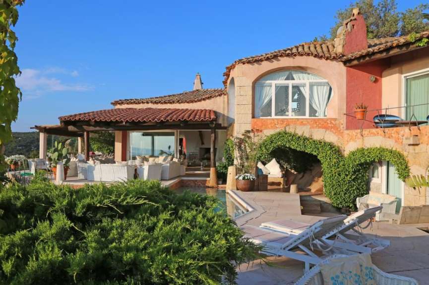 Ein luxuriöses Anwesen mit Pool, Lounge-Möbeln und mediterraner Architektur unter blauem Himmel.