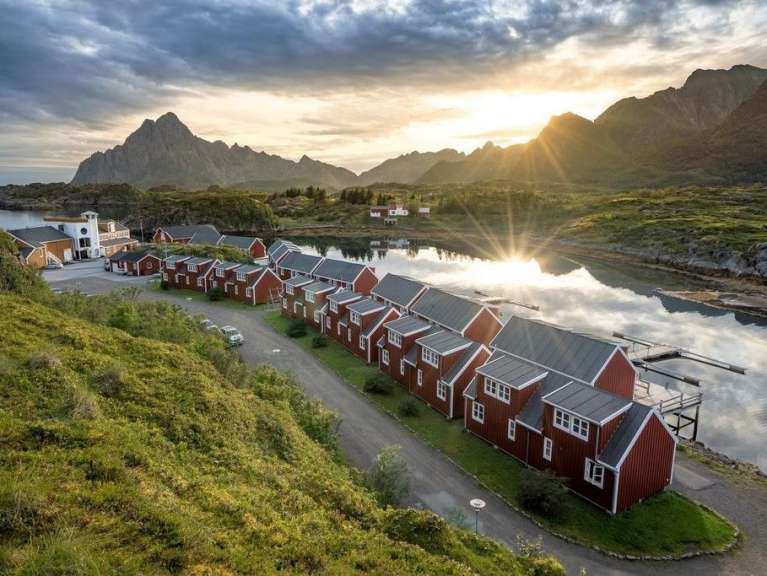 Eine Reihe roter Häuser neben einem See mit Bergen im Hintergrund