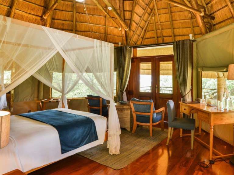 Ein luxuriöses Safari-Zelt mit einem Himmelbett und Holzböden.