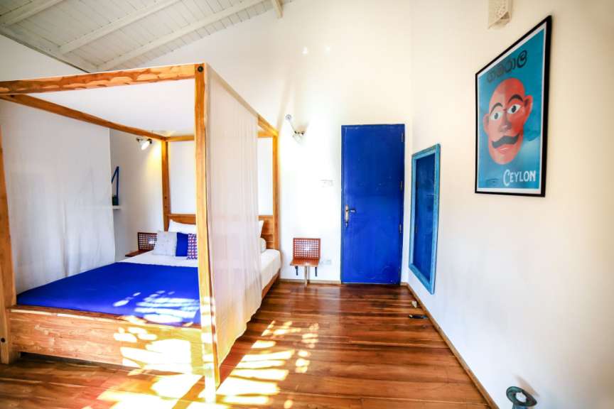 Ein Schlafzimmer mit einem Himmelbett, einer blauen Tür und einem Poster an der Wand.