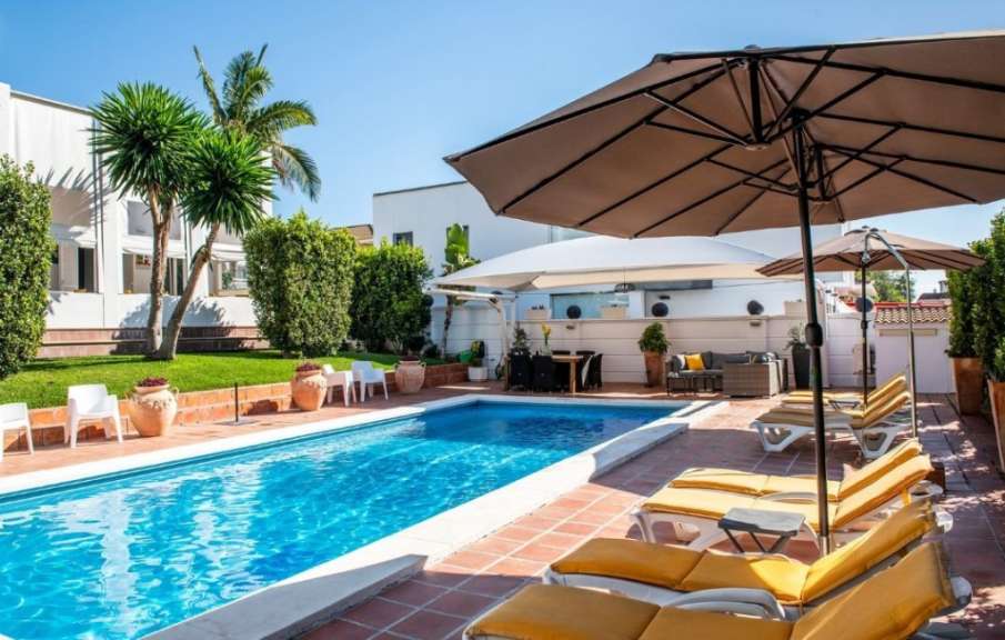 Liegestühle und Sonnenschirme umgeben einen großen Swimmingpool