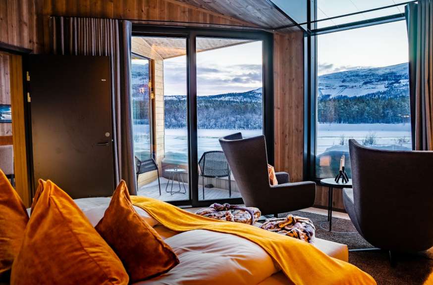 Ein Raum mit einem großen Fenster und einem Bett mit gelben Kissen