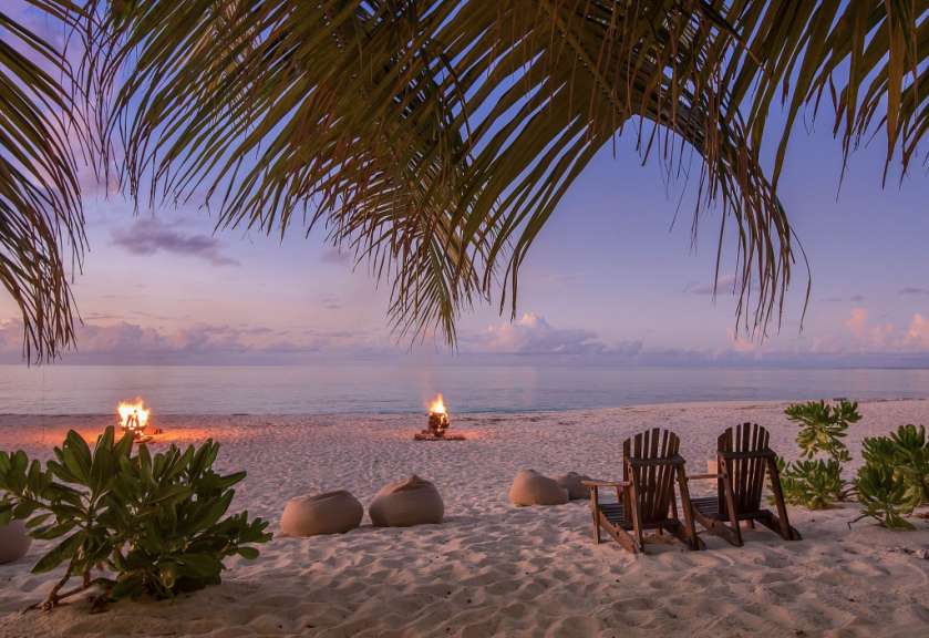 Ein Strand mit Stühlen und einem Feuer im Hintergrund