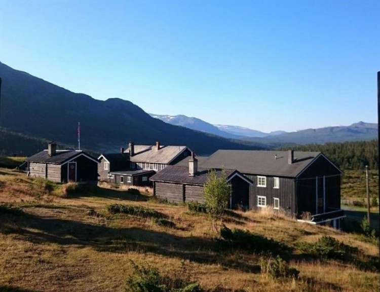 Eine Gruppe von Häusern auf einem Hügel mit Bergen im Hintergrund