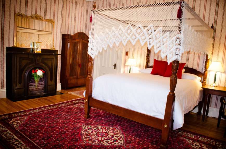 Ein Schlafzimmer mit einem Himmelbett und einem Kamin