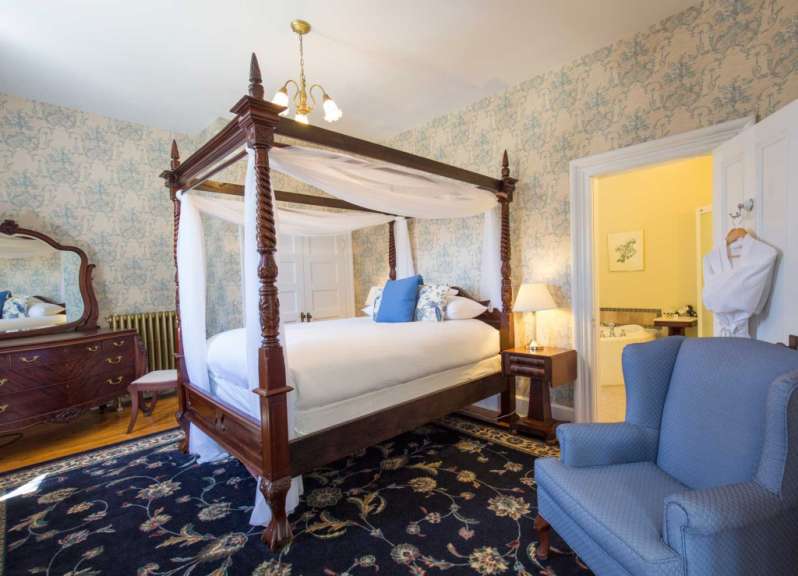 Ein Schlafzimmer mit Himmelbett und blauem Stuhl