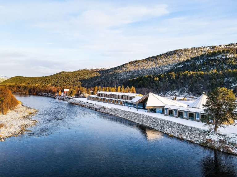 Ein Gebäude neben einem Fluss mit Bergen im Hintergrund