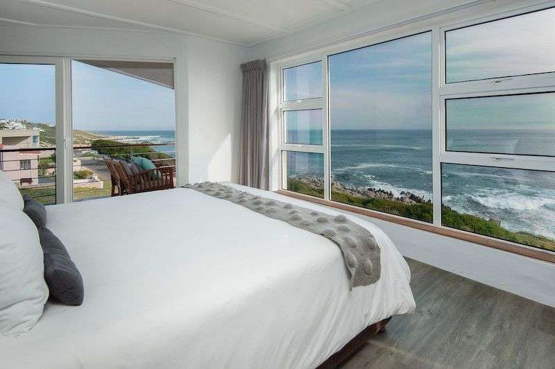 Ein Schlafzimmer mit einem Bett und einem großen Fenster mit Blick auf das Meer