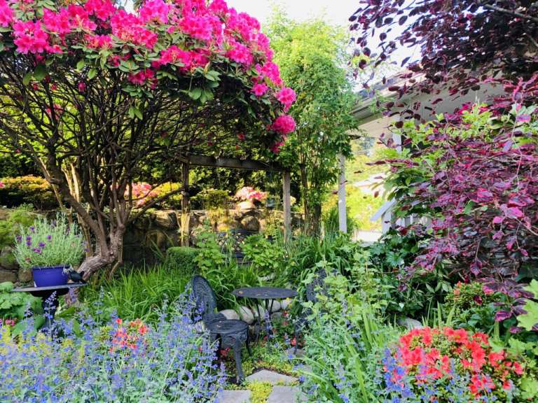 Ein Garten mit einem Tisch und Stühlen und vielen Blumen