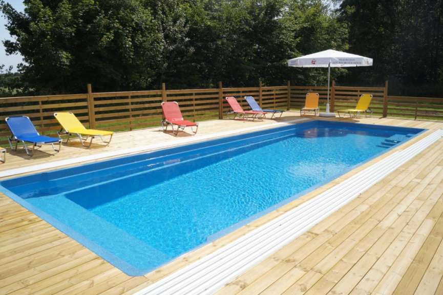 Ein blauer Pool mit Liegestühlen und einem weißen Regenschirm
