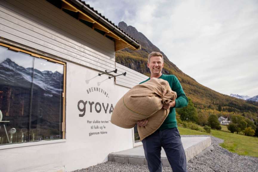 Ein mann hält einen großen sack vor einem gebäude mit dem wort grova darauf