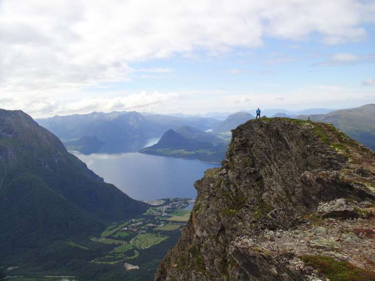 Ein Mann steht auf einer Klippe mit Blick auf einen See