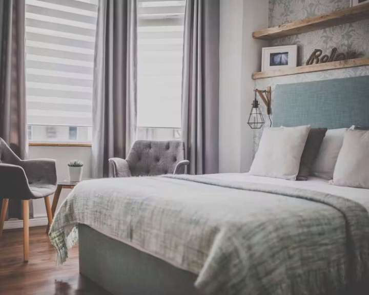 Ein Schlafzimmer mit zwei Sesseln, einem Bett und einem Fenster.