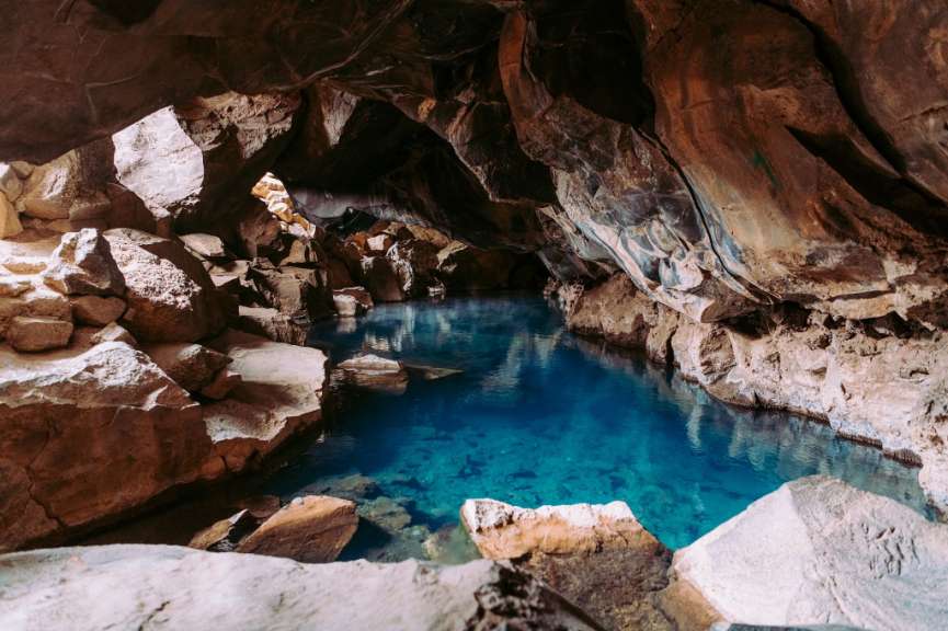 Eine Höhle mit einem blauen Wasserbecken in der Mitte