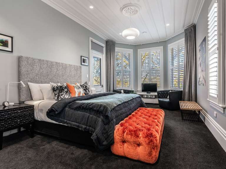Ein Schlafzimmer mit einem großen Bett und einem orangefarbenen Hocker