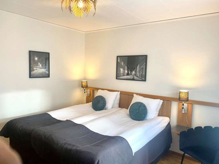 Ein Hotelzimmer mit zwei Betten und zwei Bildern an der Wand