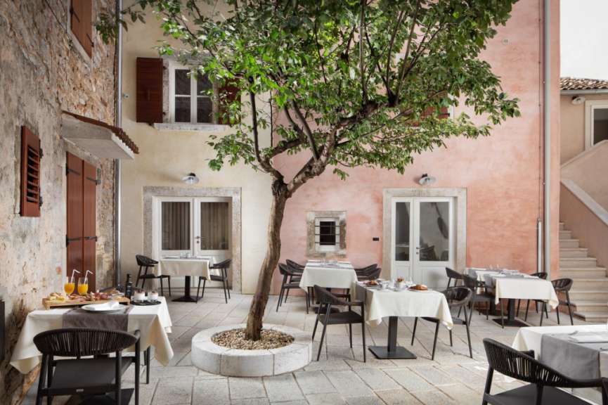 Eine Terrasse mit Tischen und Stühlen und einem Baum in der Mitte