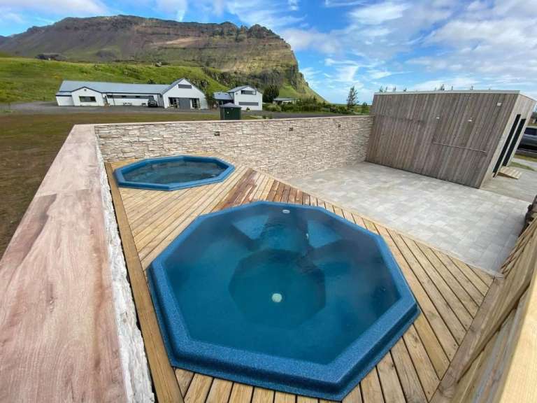 Zwei Whirlpools auf einem Holzdeck mit einem Berg im Hintergrund