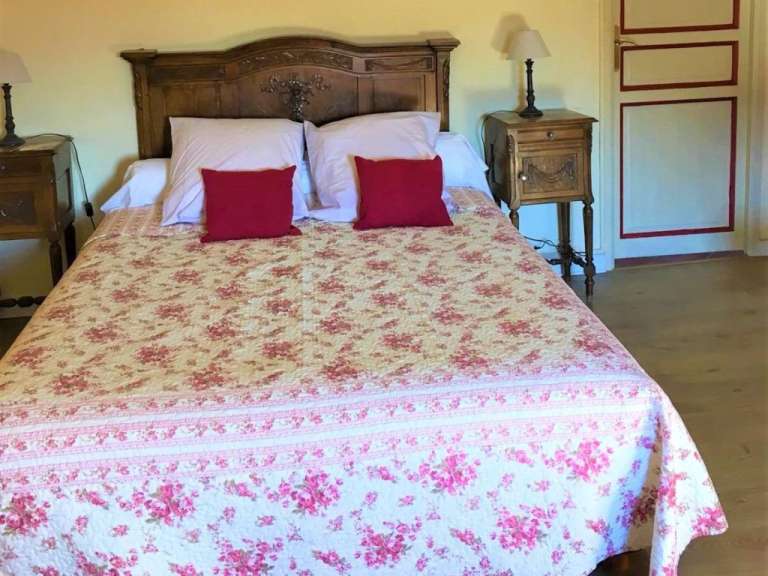 Ein Bett mit einer Blumendecke und roten Kissen darauf