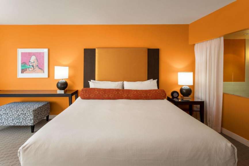 Ein Hotelzimmer mit orangefarbenen Wänden und einem Bett