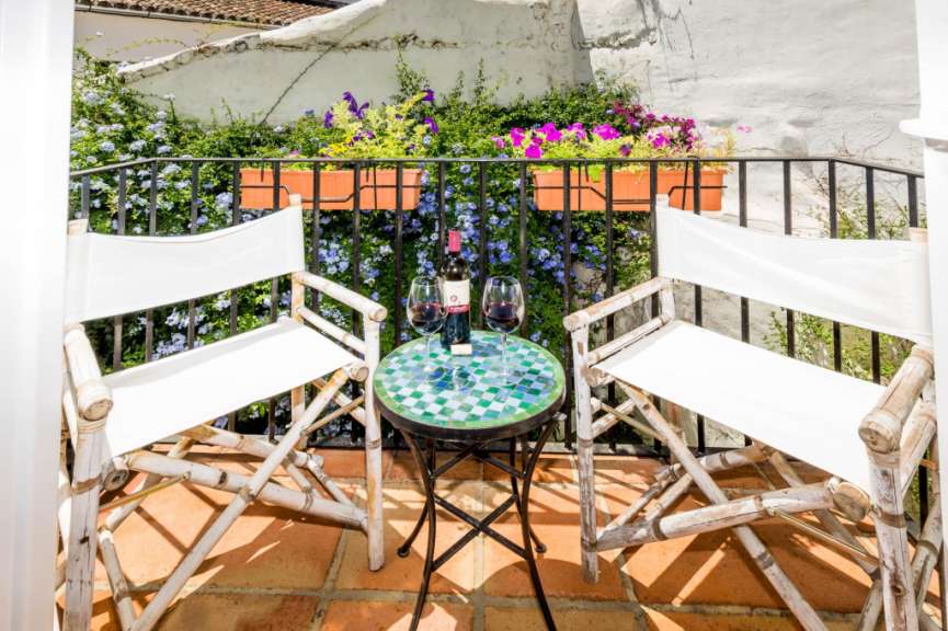 Ein Tisch mit zwei Gläsern und einer Flasche Wein auf einem Balkon