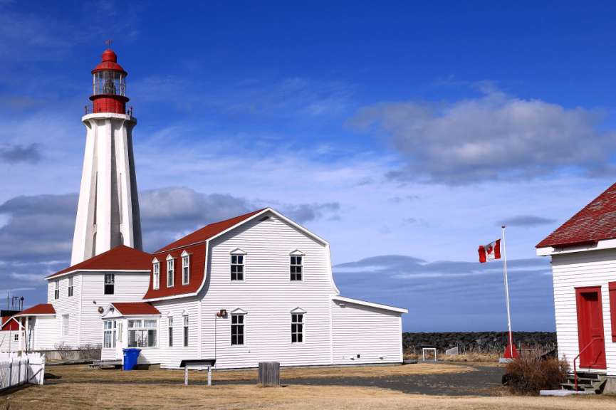Ein weißes Gebäude mit einem roten Dach und einem Leuchtturm dahinter