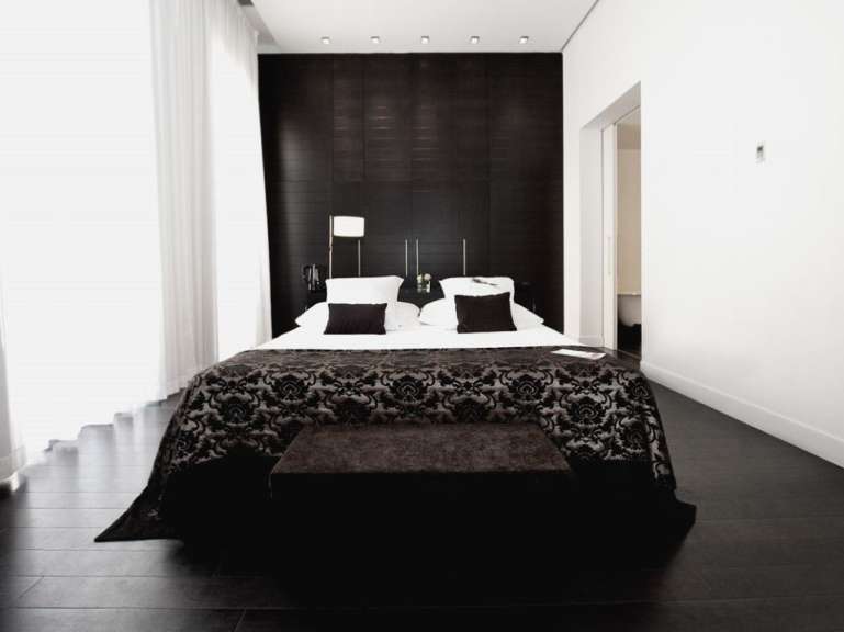 Ein schwarz-weißes Schlafzimmer mit einem Bett und einer Bank