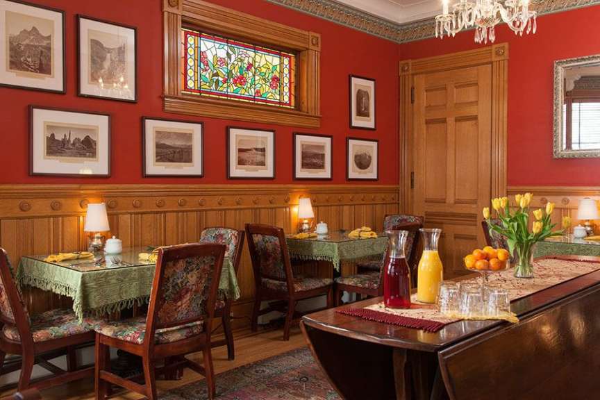 Ein Esszimmer mit roten Wänden und einem Buntglasfenster