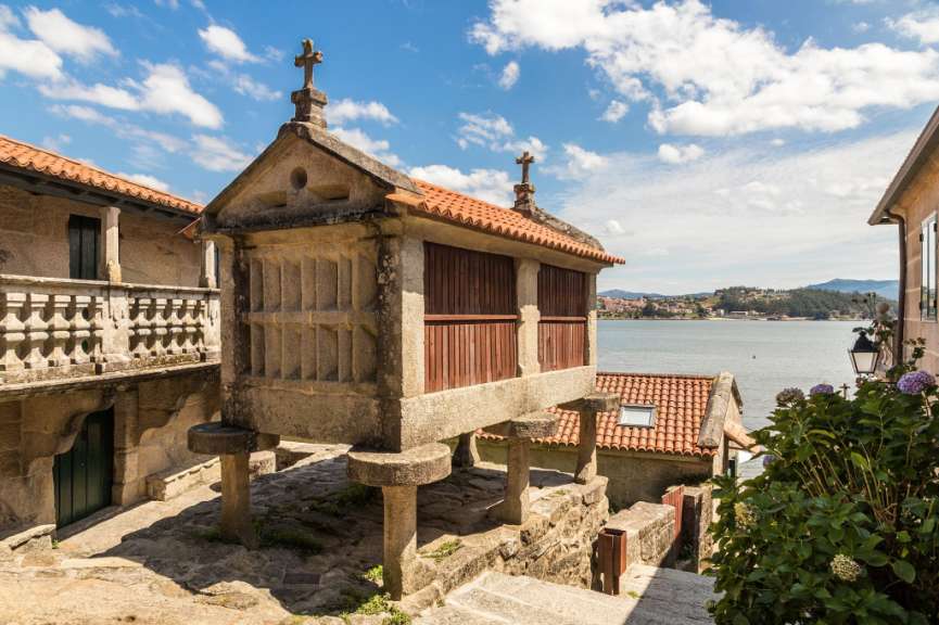 Ein Steingebäude mit einem Holzdach und einem Kreuz darauf